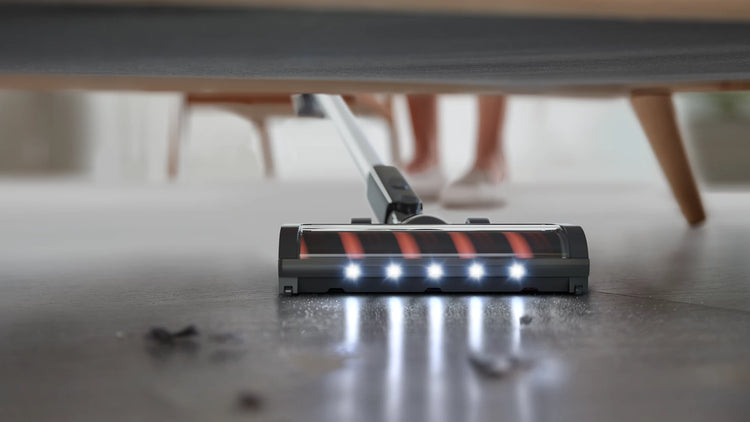 Vacuum cleaner under a piece of furniture on a wooden floor