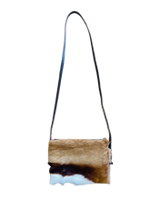 Crossbody bag with a natural cowhide pattern on a white background