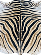 Close-up of a zebra skin pattern with black and beige stripes.
