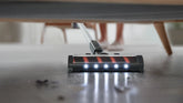 Vacuum cleaner under a piece of furniture on a wooden floor